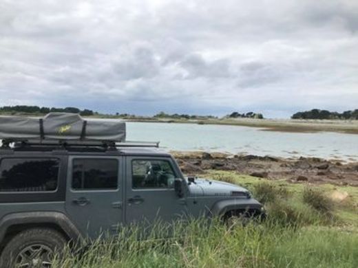 Jeep mit zusammengeklapptem Dachzelt am Strand