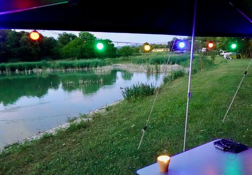 Blick auf See mit Lichterkette unter der Markise des Anhängerzelts