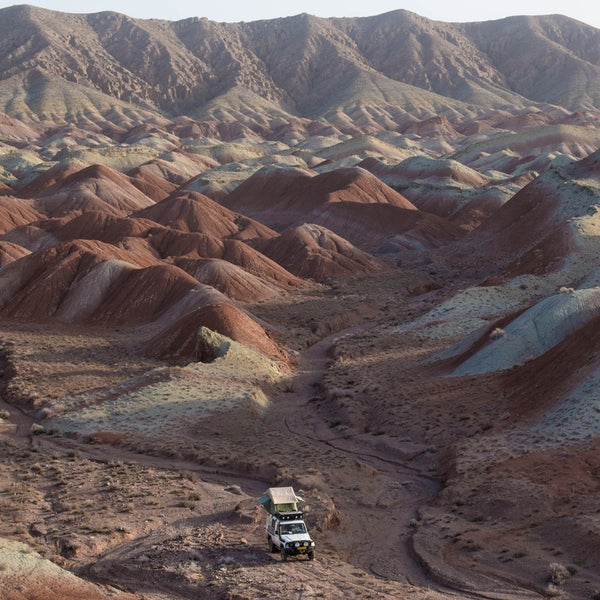 Irans Berg- und Hügellandschaft und mittendrin ein Geländewagen mit Dachzelt allein auf weiter Flur