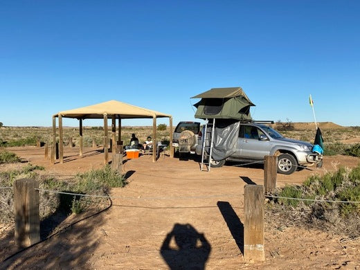 Dachzelt auf Auto in Australien neben einem überdachten Picknickplatz in der Wüste