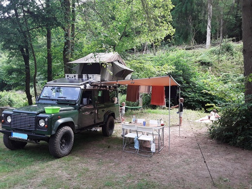 Defender mit Dachzelt und Markise im Wald