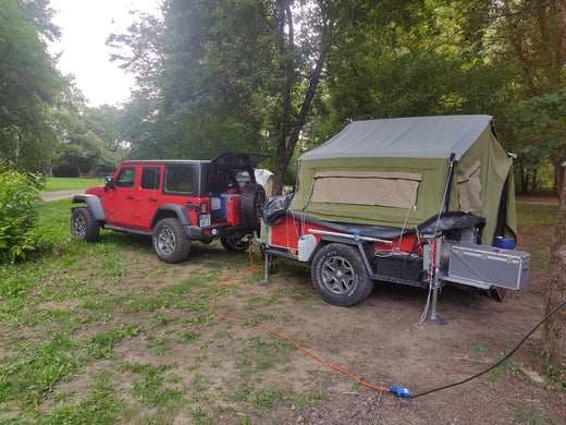Anhängerzelt gezogen von einem roten Jeep Wrangler