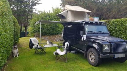 Defender mit Faltdachzelt und Markise, Campingtisch und Campingstühlen