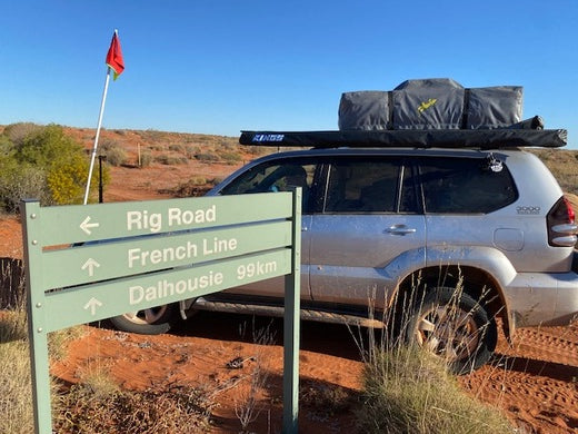 Auto mit Dachzelt zusammengeklappt neben Wegweisern in Australien