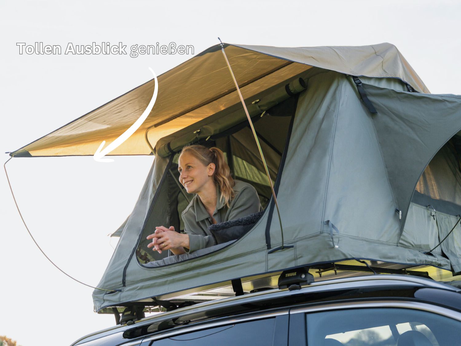 Frau schaut aus großem Dachzeltfenster in die Ferne